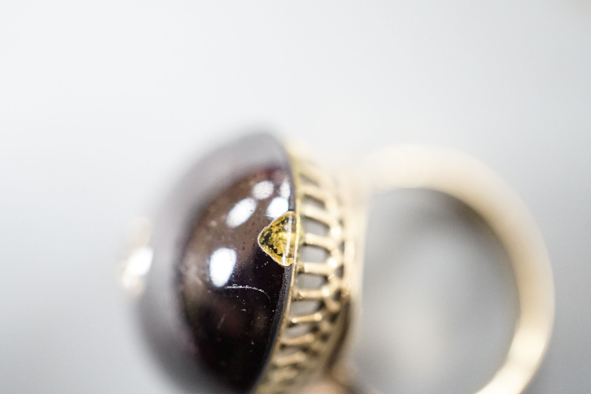 A yellow metal, foil backed cabochon garnet and diamond set oval dress ring, size P/Q, gross 11.1 grams, (a.f.).